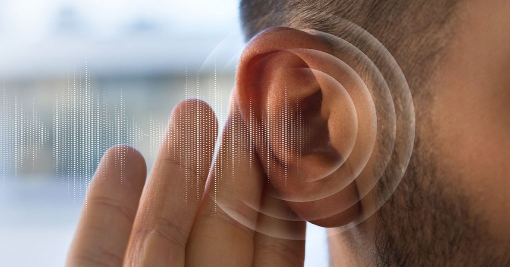 Close-up image of a human ear with digital sound waves illustrated around it, symbolizing auditory perception or the detection of subtle sounds.